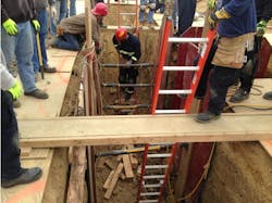 Photo 4: A bridge is built across the trench and a ladder is secured on each side, providing a safe haven to work from until the walls are shored.