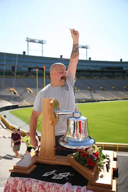 Pierce Manufacturing is hosting its fourth annual 9/11 Memorial Stair Climb at historic Lambeau Field on Saturday, September 10, 2016. All funds raised will benefit the National Fallen Firefighters Foundation (NFFF) and the families of fallen firefighters. Pictured is Pierce employee, Sam Boucher, as he rings a symbolic bell and raises a badge representing the fallen firefighter for whom he climbed at last year&rsquo;s event.