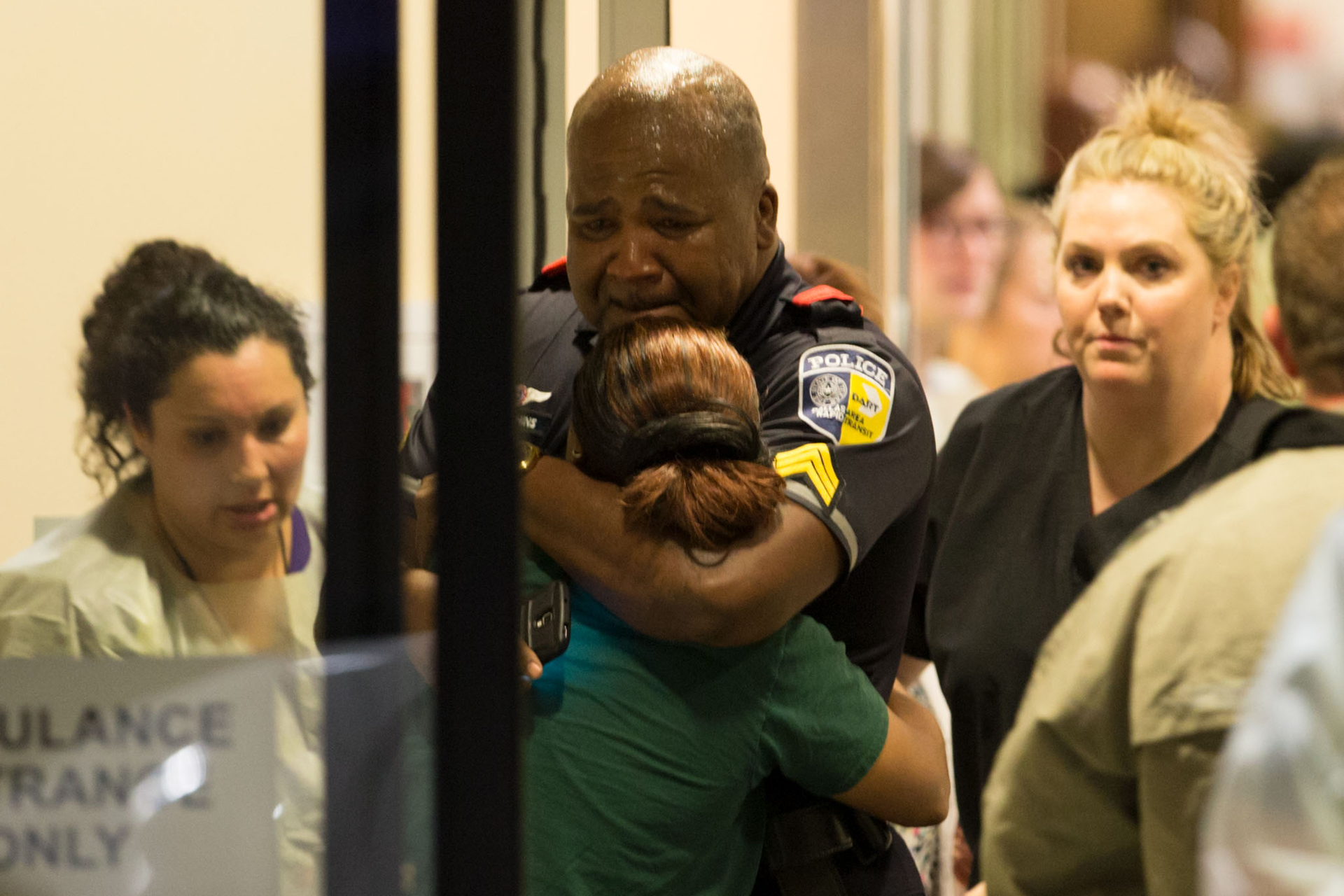 A police officer is comforted as he arrives at a hospital.