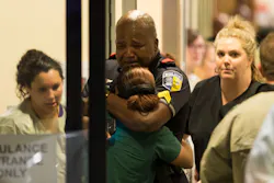 A police officer is comforted as he arrives at a hospital.