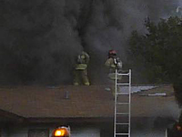 Two engine company firefighters perform ventilation at dwelling fire. Training in the rapid deployment of ground ladders while carrying the necessary tools can expedite the ventilation process.