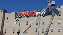 Nashville firefighters and Firehouse Ambassadors work to hang an Expo banner from an acquired structure for hands on training.