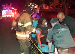 Fort Worth firefighters and MedStar paramedics assist a resident to the ambulance.