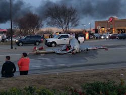 A large section of a plane lays in the middle of a road. A large section of a plane lays in the middle of a road.