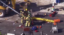 Firefighters work at the scene where three workers died and one firefighter was overcome by fumes inside a manhole in Lake Surprise.