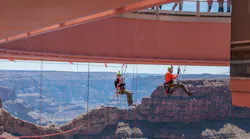 Two level III rope access technicians meet at the halfway point pre-rigging protection lines under the Grand Canyon Skywalk. The Skywalk is a glass walkway cantilever bridge built over the Grand Canyon in 2007. The underside of the glass had never been cleaned, and Abseilon USA was contracted to do this high-exposure job.