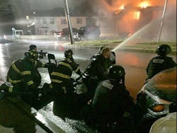 Chelsea firefighters are protected by SWAT officers with shields while trying to to douse a fire set Monday night by a man engaged in an hours-long armed standoff with police.