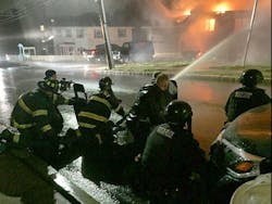 Chelsea firefighters are protected by SWAT officers with shields while trying to to douse a fire set Monday night by a man engaged in an hours-long armed standoff with police.