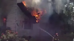 A section of roof falls before narrowly missing an Anderson firefighter working to tackle a fire during which neighbors rescued an elderly woman Tuesday.