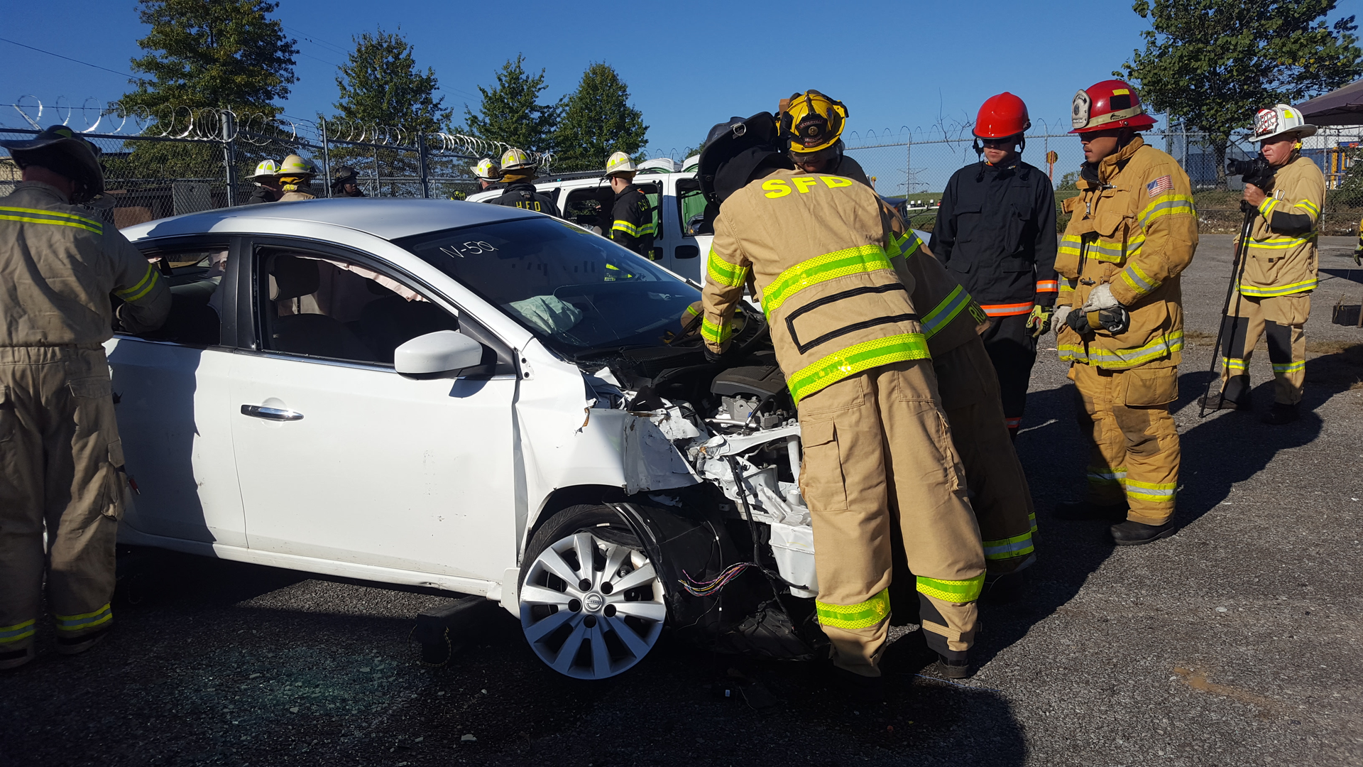 A team of firefighters work on a late model Nissan sedan to disconnect 12-volt power before a simulated rescue begins during the University of Extrication during Firehouse Expo in Nashville.