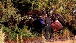 A Suffolk County police officer inspects a mangled car that was hit by a LIRR train in Bellport, NY, on Tuesday night moments after an off-duty Brookhaven firefighter pulled the driver out of the vehicle.