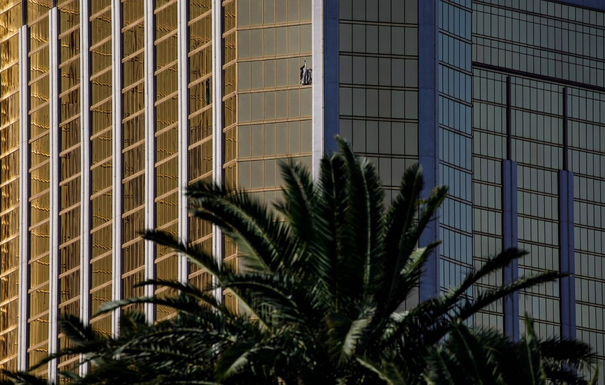 A curtain blows out of a broken window where a gunman opened fire from an upper story of the Mandalay Bay resort on a country music festival across the street on the Las Vegas Strip on Sunday night, leaving at least 58 dead and more than 500 injured.
