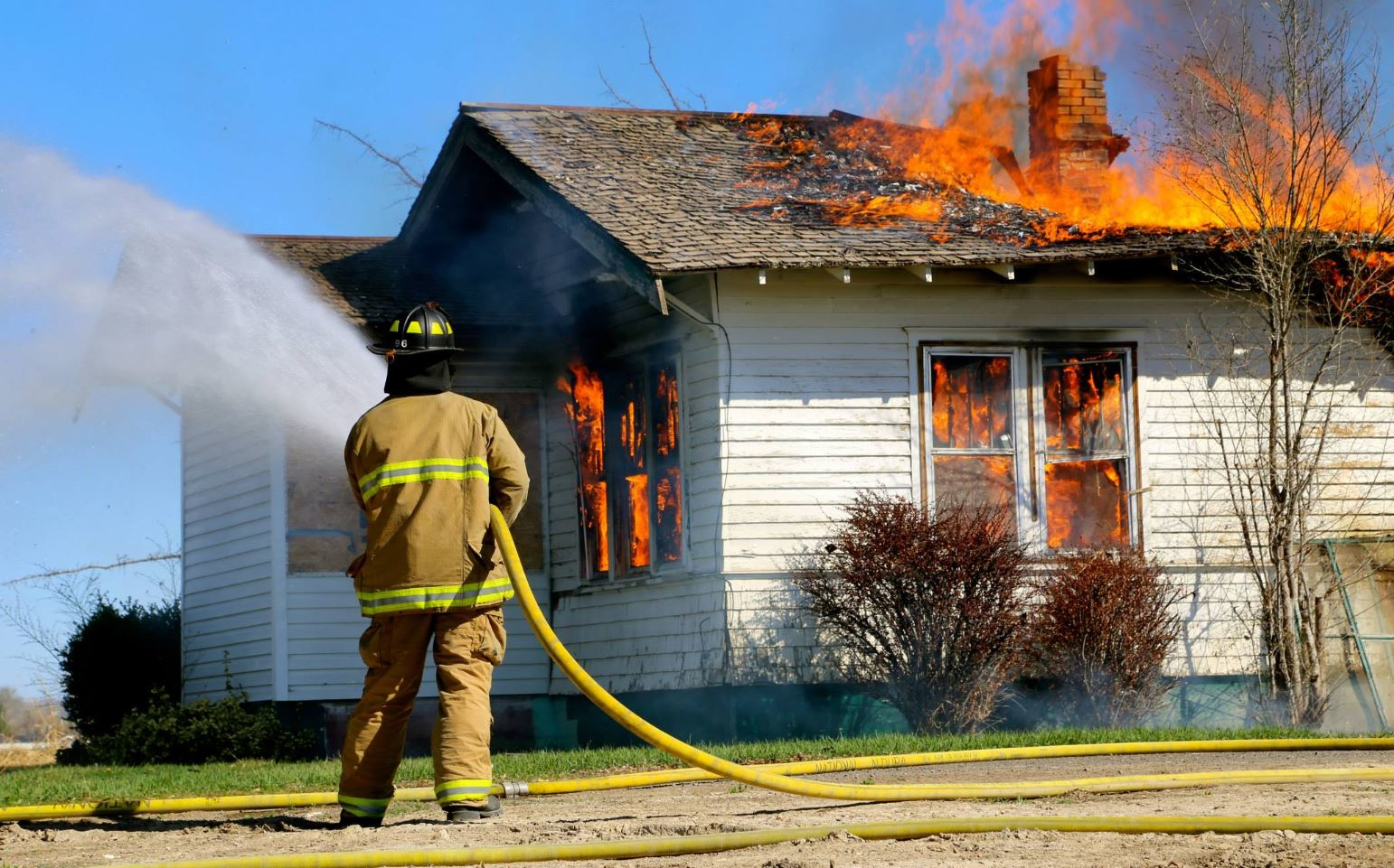 A Twin Falls, ID, firefighter begins pouring water on a house fire in March 2015.