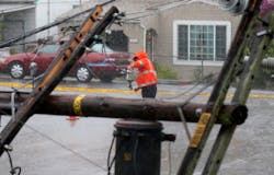 A Pacific Gas and Electric Company worker picks up parts from a power line after a tree knocked down a utility pole on Thursday, Dec. 11, 2014, in San Leandro, CA.