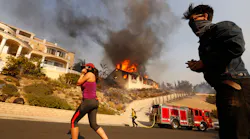 Amanda Leon and husband Johnny Leon watch as firefighters fight to save multi-million dollar homes along Cobblestone Drive Tuesday midday after a fast-moving swept into Ventura destroying many homes.