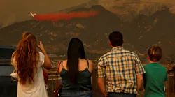 Onlookers watch as a tanker drops flame retardant material on hot spots in Carpenteria, CA, on Dec. 11, 2017, during efforts to contain the Thomas Fire.