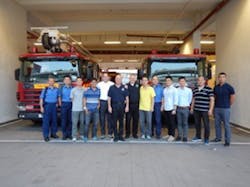 A group photo of instructors and students in front of the fire academy in Hong Kong.