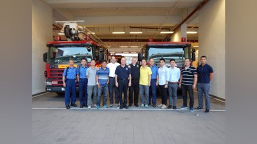 A group photo of instructors and students in front of the fire academy in Hong Kong.