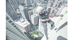 A rope access technician is suspended over the edge of a Chicago skyscraper.