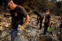 Jeff Lipscomb, from left, Gabriel Lipscomb, 17, and Rachel Lipscomb, 11, look for items to recover in the wreckage of their burned home on Dec. 6, 2017, in Ventura, CA.