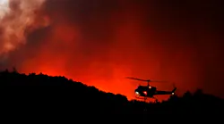 A helicopter prepares to drop water on a fire threatening the Oakmont community along Highway 12 in Santa Rosa, CA, on Oct. 13, 2017.
