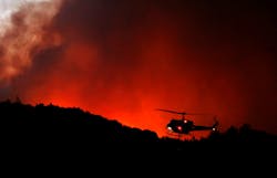 A helicopter prepares to drop water on a fire threatening the Oakmont community along Highway 12 in Santa Rosa, CA, on Oct. 13, 2017.