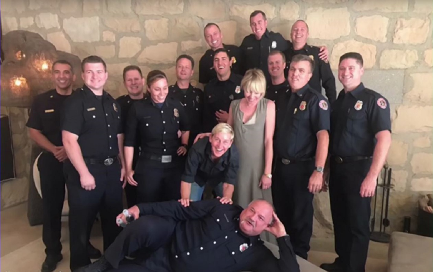 TV host Ellen DeGeneres and her spouse Portia de Rossi pose with a group of firefighters who helped protect their Santa Barbara, CA, home from the Thomas Fire.