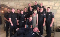 TV host Ellen DeGeneres and her spouse Portia de Rossi pose with a group of firefighters who helped protect their Santa Barbara, CA, home from the Thomas Fire.