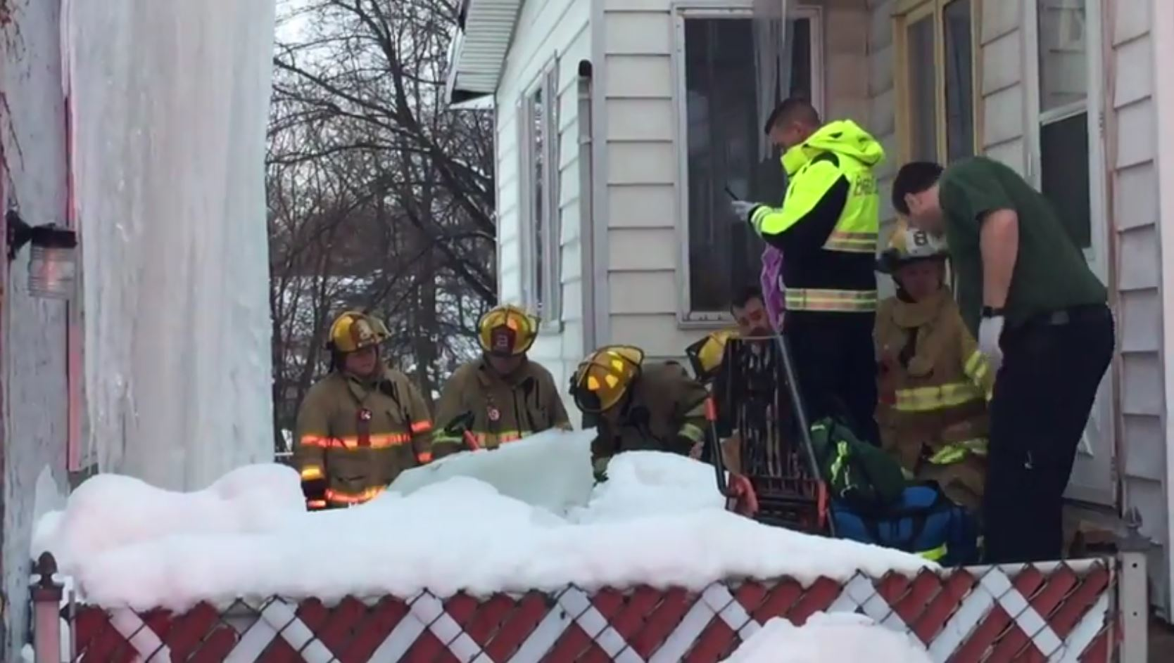 Erie, PA, firefighters chop through a massive chunk of ice that pinned a man's legs Monday as he was trying to dislodge it from a house.