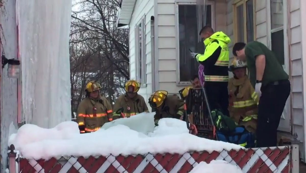 Erie, PA, firefighters chop through a massive chunk of ice that pinned a man&apos;s legs Monday as he was trying to dislodge it from a house.
