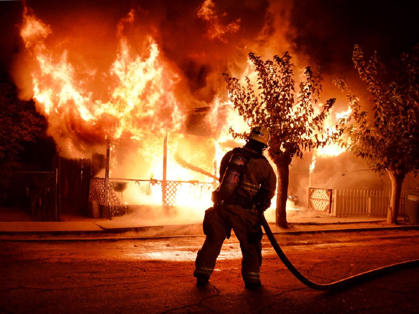 A Kern County firefighter puts water on a house fire near Taft, CA, in November 2017.