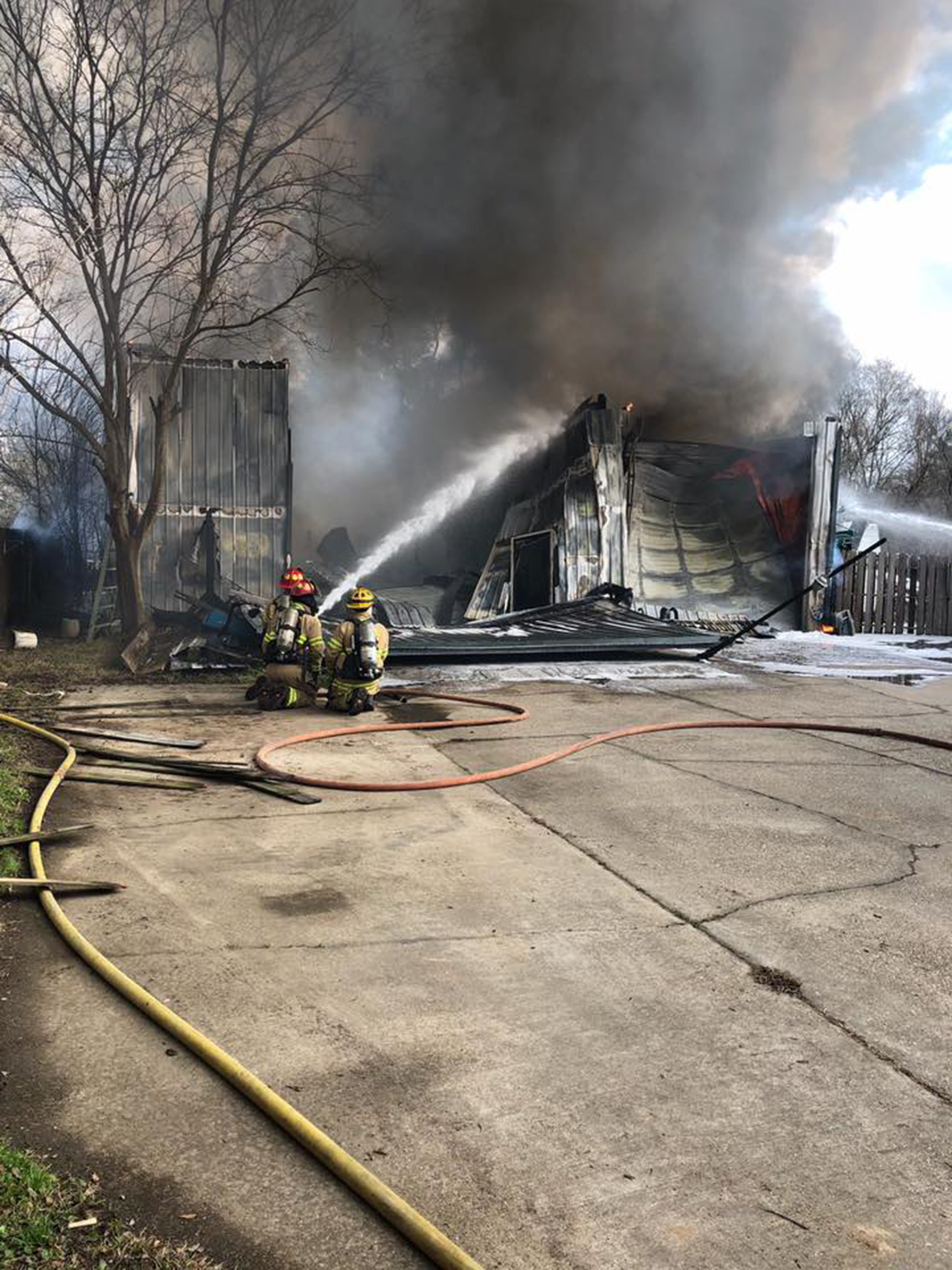 Crews battle a garage fire where a firefighter was trapped when a section of roof fell.