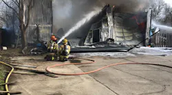 Crews battle a garage fire where a firefighter was trapped when a section of roof fell.
