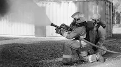 Firefighters applying gas cooling during training. The cone angle is approximately 60 degrees and is inclined 45 degrees with the ground.
