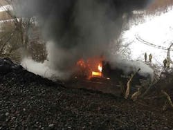 Firefighters look on as a Norfolk Southern freight engine burns after derailing in Attica, NY, on Thursday, Feb. 15, 2018.