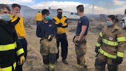 Fire crews wear breathing masks as they work near a contained tire fire in El Paso County, CO that continues to smolder and release hazardous materials.
