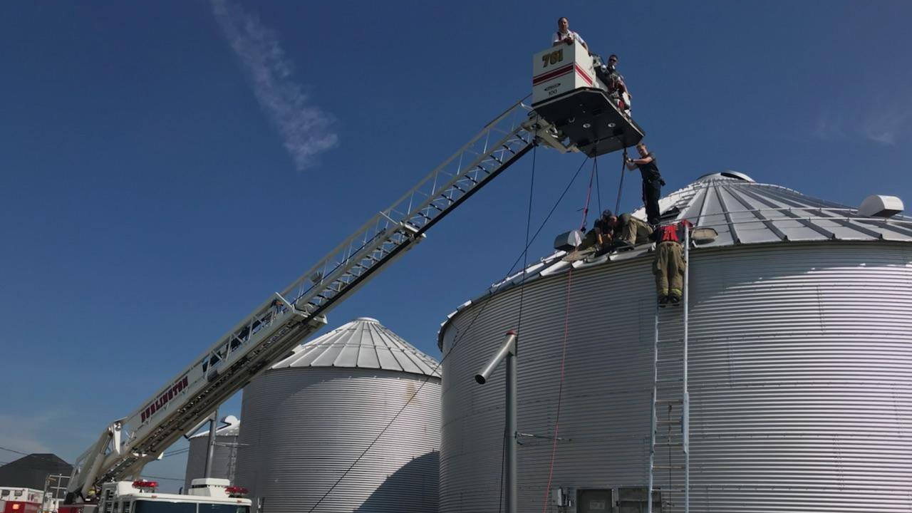 Firefighters use ladders to reach the top of a grain bin and rescue a man who became trapped inside on Wednesday, May 30, 2018.