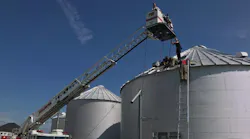 Firefighters use ladders to reach the top of a grain bin and rescue a man who became trapped inside on Wednesday, May 30, 2018.