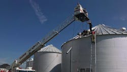 Firefighters use ladders to reach the top of a grain bin and rescue a man who became trapped inside on Wednesday, May 30, 2018.