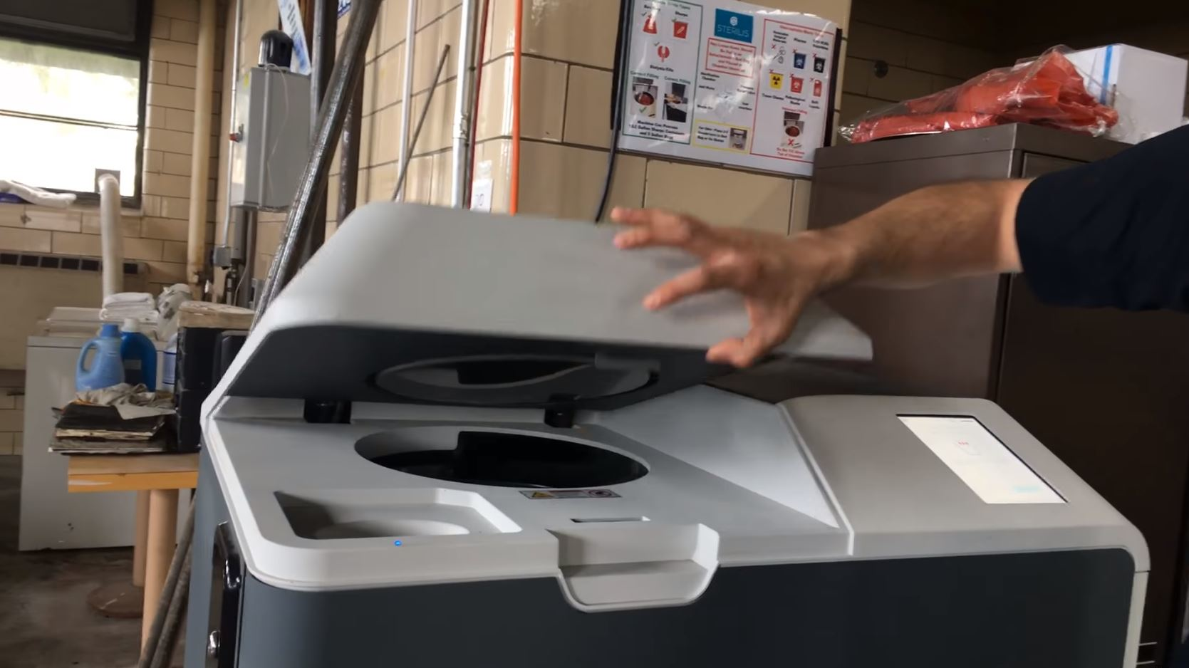 A firefighter demonstrates use of a needle and syringe disposal unit at a fire station in Fall River, MA.