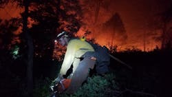A firefighter uses a power saw to clear brush while working to create a containment line against the 416 fire burning north of Durango, CO, on June 11, 2018.