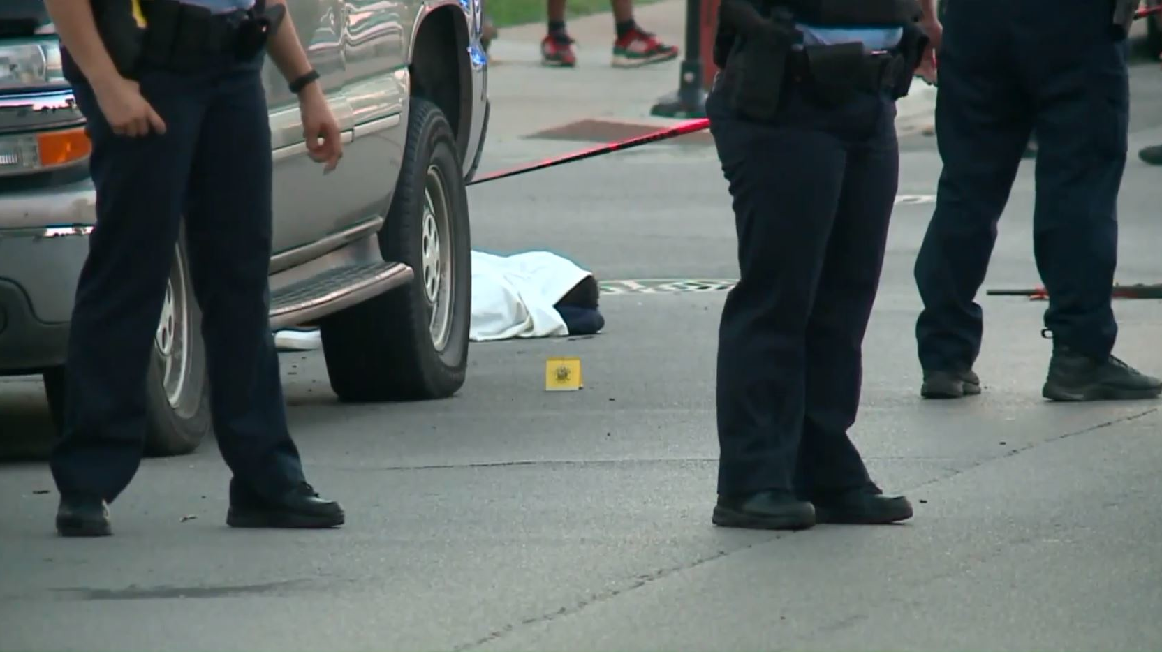 Chicago police officers stand near 17-year-old Erin Carey after the teen was shot multiple times in the head on Monday, June 18, 2018, and covered with a sheet because paramedics mistakenly believed he was dead.