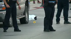 Chicago police officers stand near 17-year-old Erin Carey after the teen was shot multiple times in the head on Monday, June 18, 2018, and covered with a sheet because paramedics mistakenly believed he was dead.