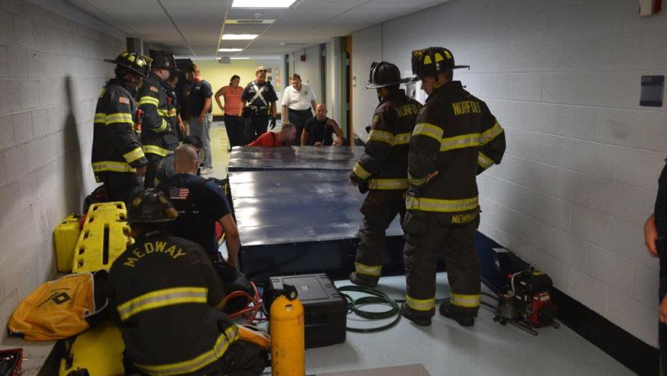 Crews work to free a custodian who became trapped when the row of lockers she was cleaning toppled over and trapped her at a middle school in Medway, MA, on Monday, June 25, 2018.