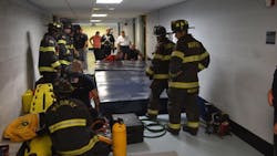 Crews work to free a custodian who became trapped when the row of lockers she was cleaning toppled over and trapped her at a middle school in Medway, MA, on Monday, June 25, 2018.
