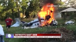 An injured man wearing a red shirt runs away from a plane wreckage in Detroit on Sunday, June 24, 2018, that killed two people.