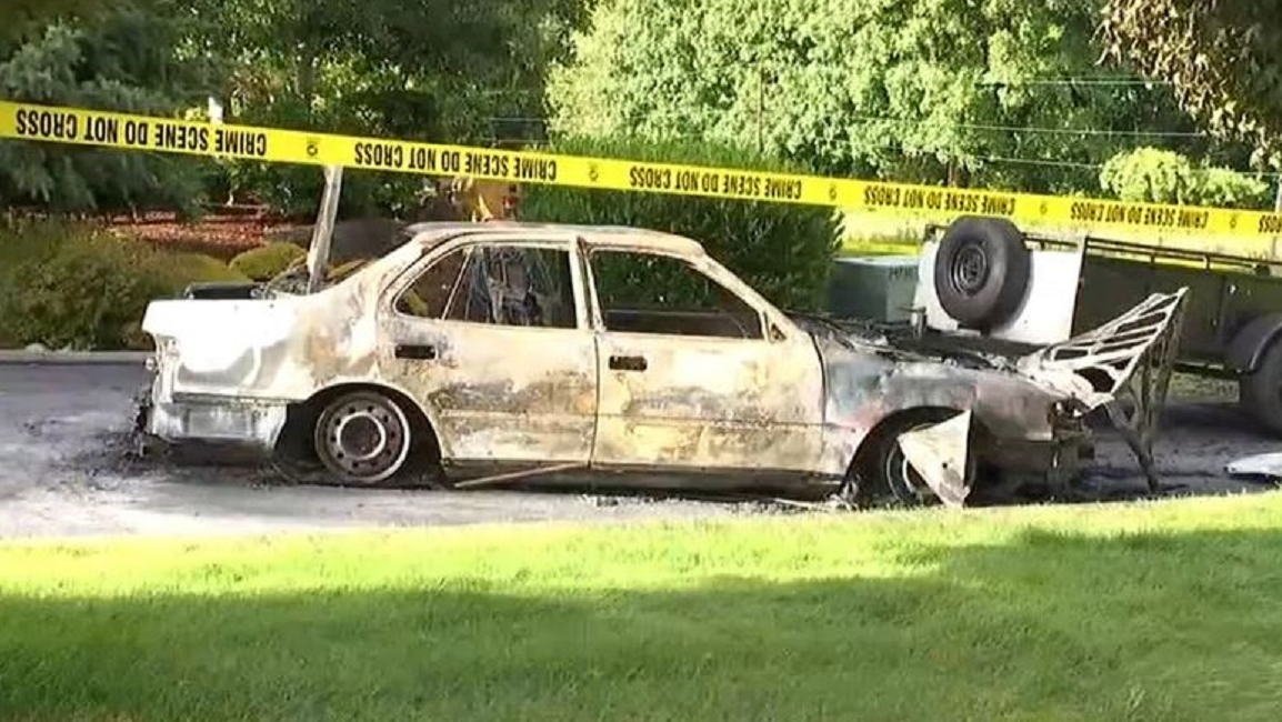 A burned-out car sits in a driveway in Ridgefield, WA, after two men set it on fire after assaulting and robbing a man on Saturday, June 9, 2018.