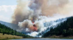 A firefighting helicopter flies in the foreground while the Spring Creek Fire rages behind it.