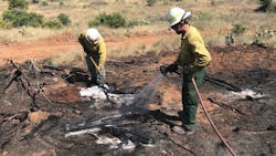 Firefighters douse a hot spot while battling the Smith West Fire in Blanco County, TX, on Wednesday, July 18, 2018.