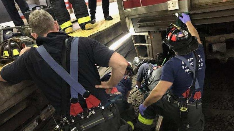Cambridge firefighters work to rescue a woman who became trapped between an MBTA train and the platform at Central Square station on Thursday, July 12, 2018.